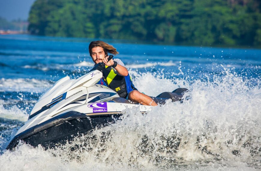 man in safety vest riding a personal watercraft during daytime