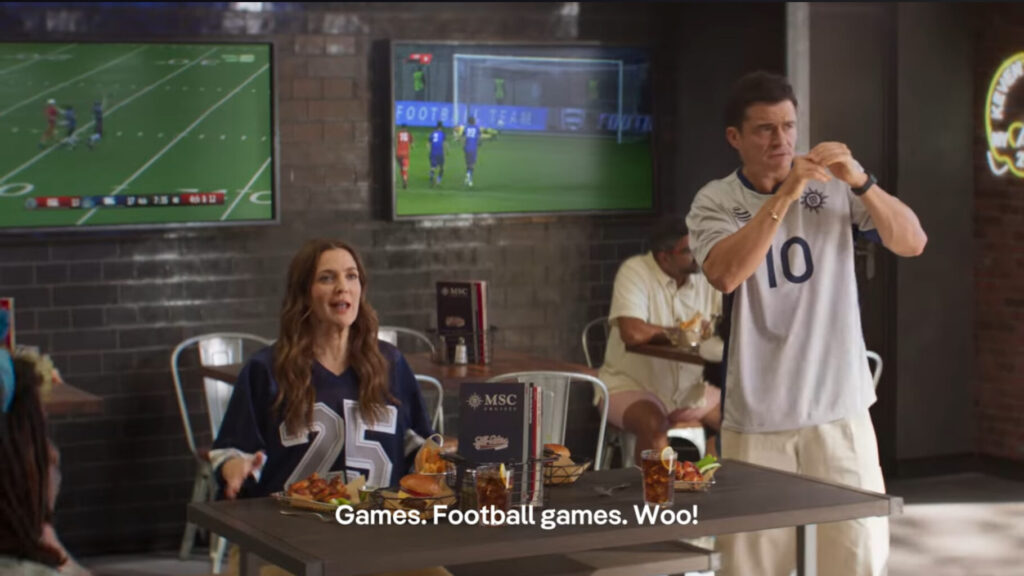 Drew Barrymore and Orlando Bloom watch a football game during a 2025 Superbowl ad for MSC World America