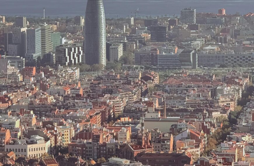 Aerial view of Barcelona showcasing the Torre Glòries and cityscape against the backdrop of the sea.