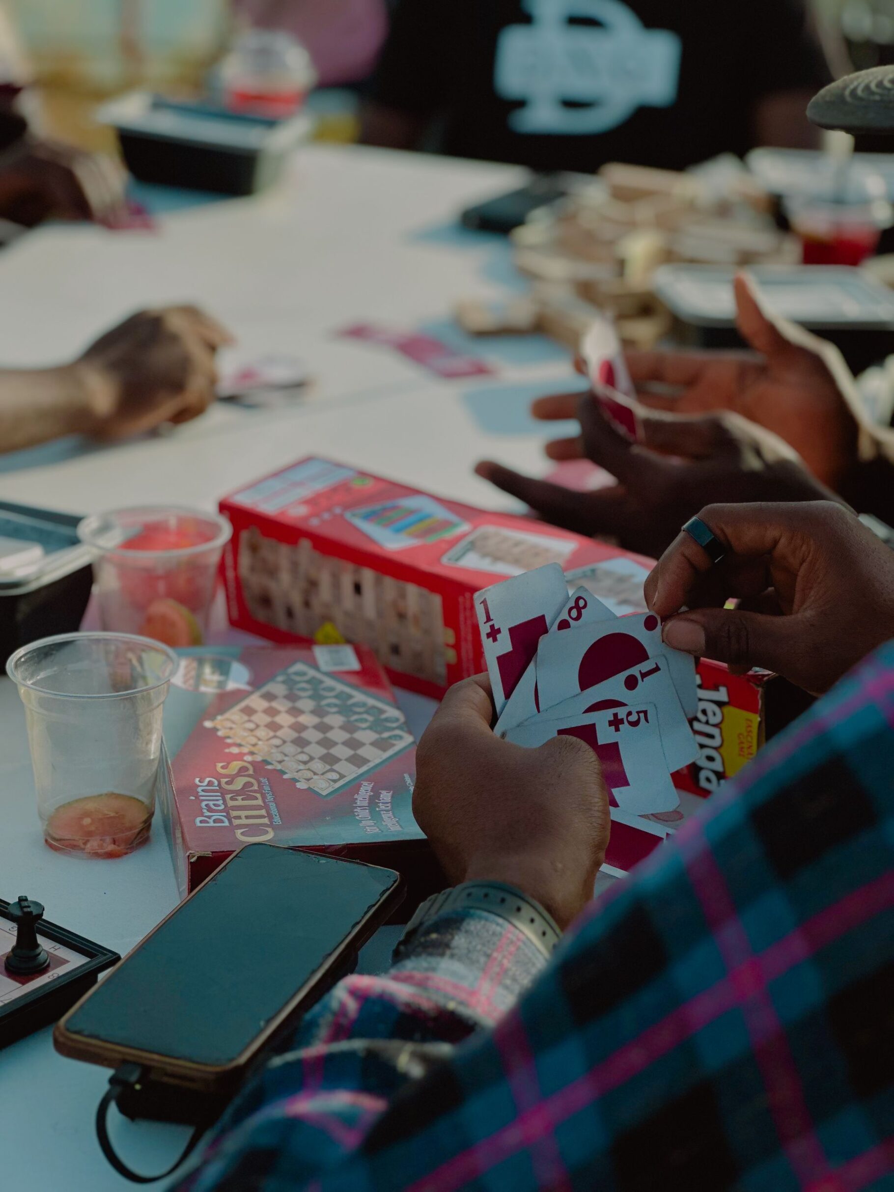 Adults enjoying card games together outdoors, creating a vibrant social atmosphere.