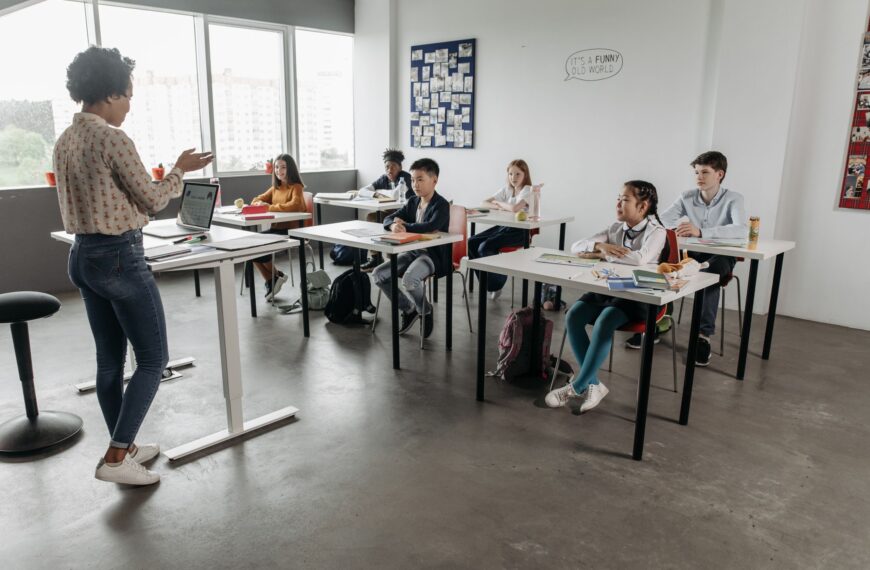 Teacher interacting with students in a modern classroom, fostering a diverse and engaging educational environment.