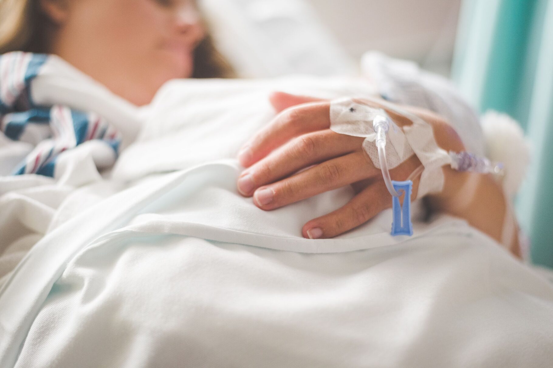 Focused shot of a patient's hand with IV in a hospital setting.