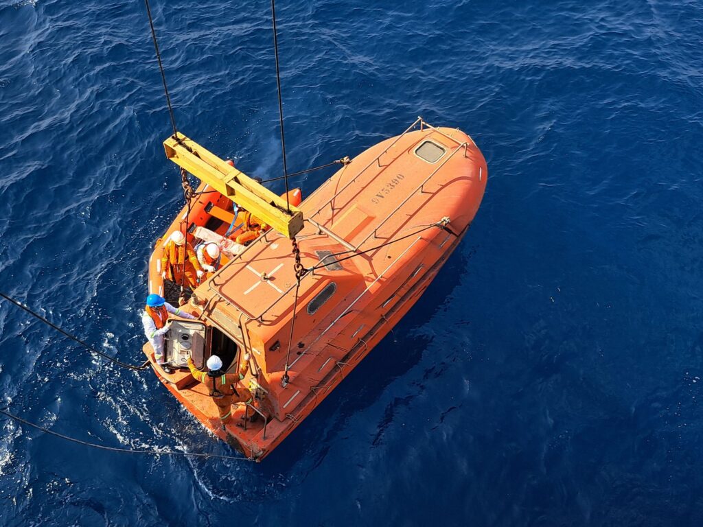 Lifeboat in the ocean with crew onboard for rescue training or emergency deployment.