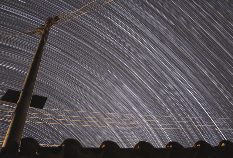 Long exposure shot of star trails over an electric post in Goiânia, Brazil.