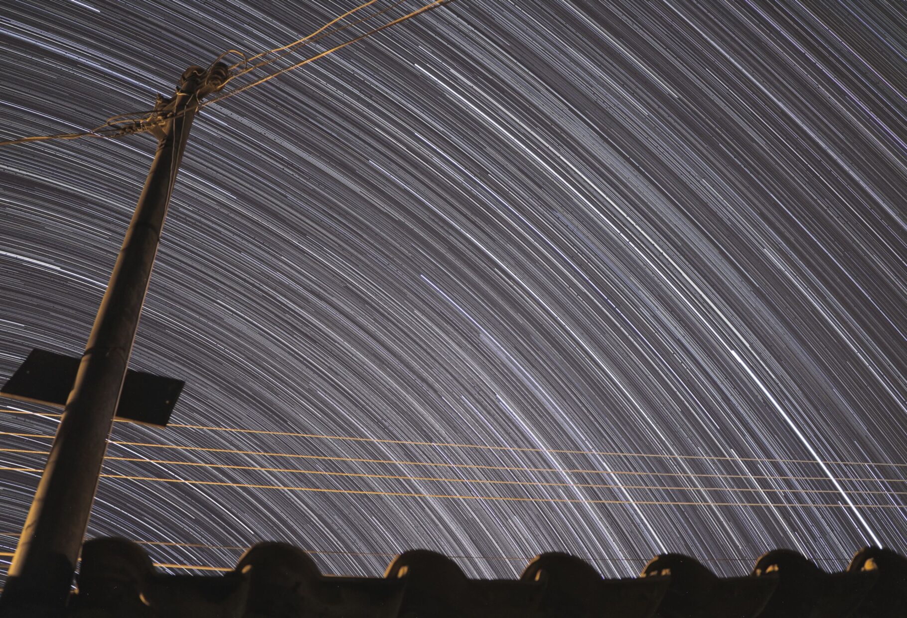Long exposure shot of star trails over an electric post in Goiânia, Brazil.